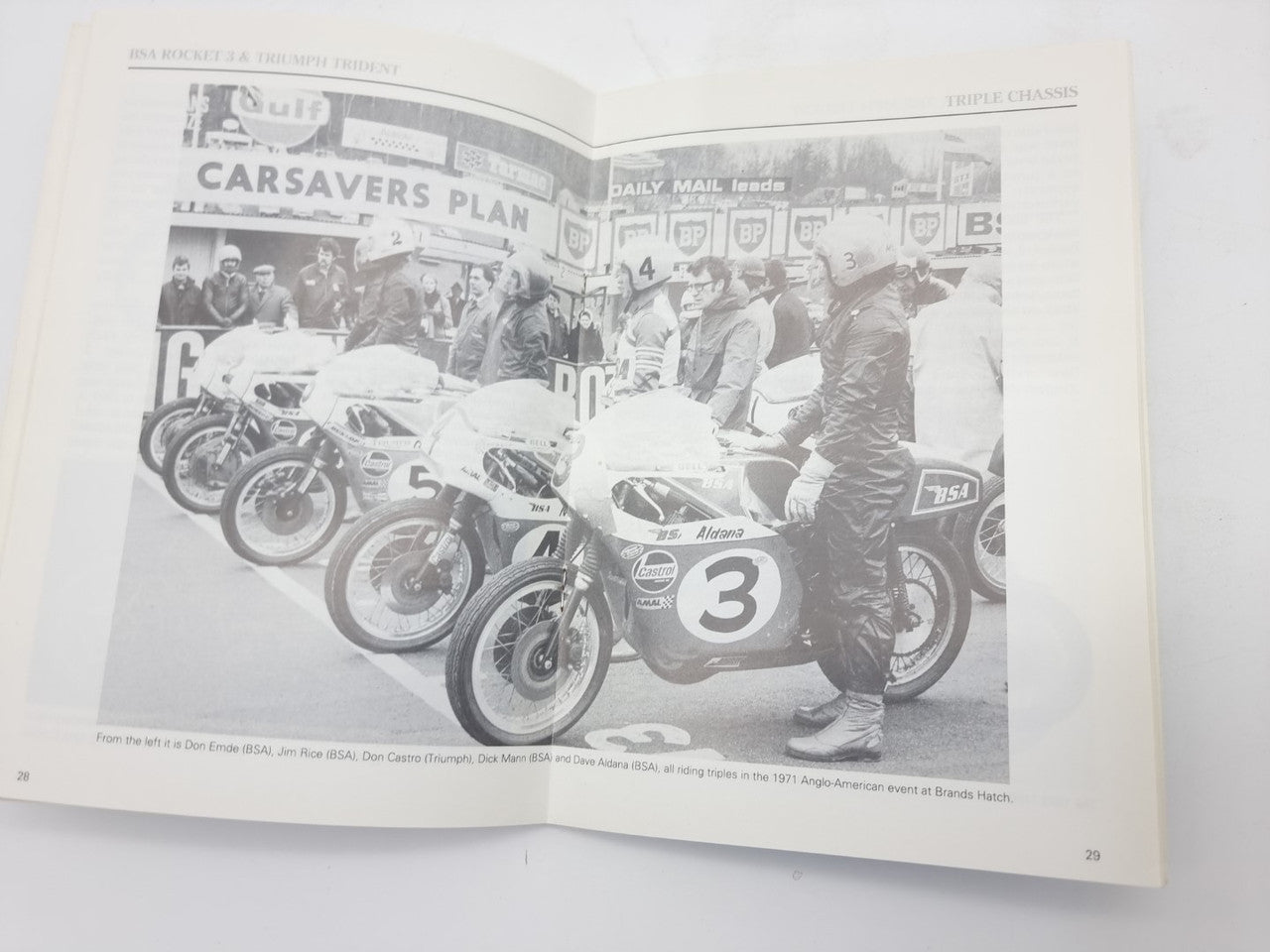 Motorcycle monograph book open to Carsavers Plan page with group of classic bikes