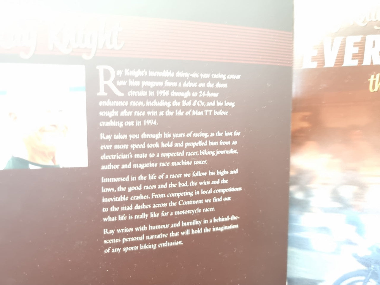 Paperback page close-up with paragraph text over a racing photo background