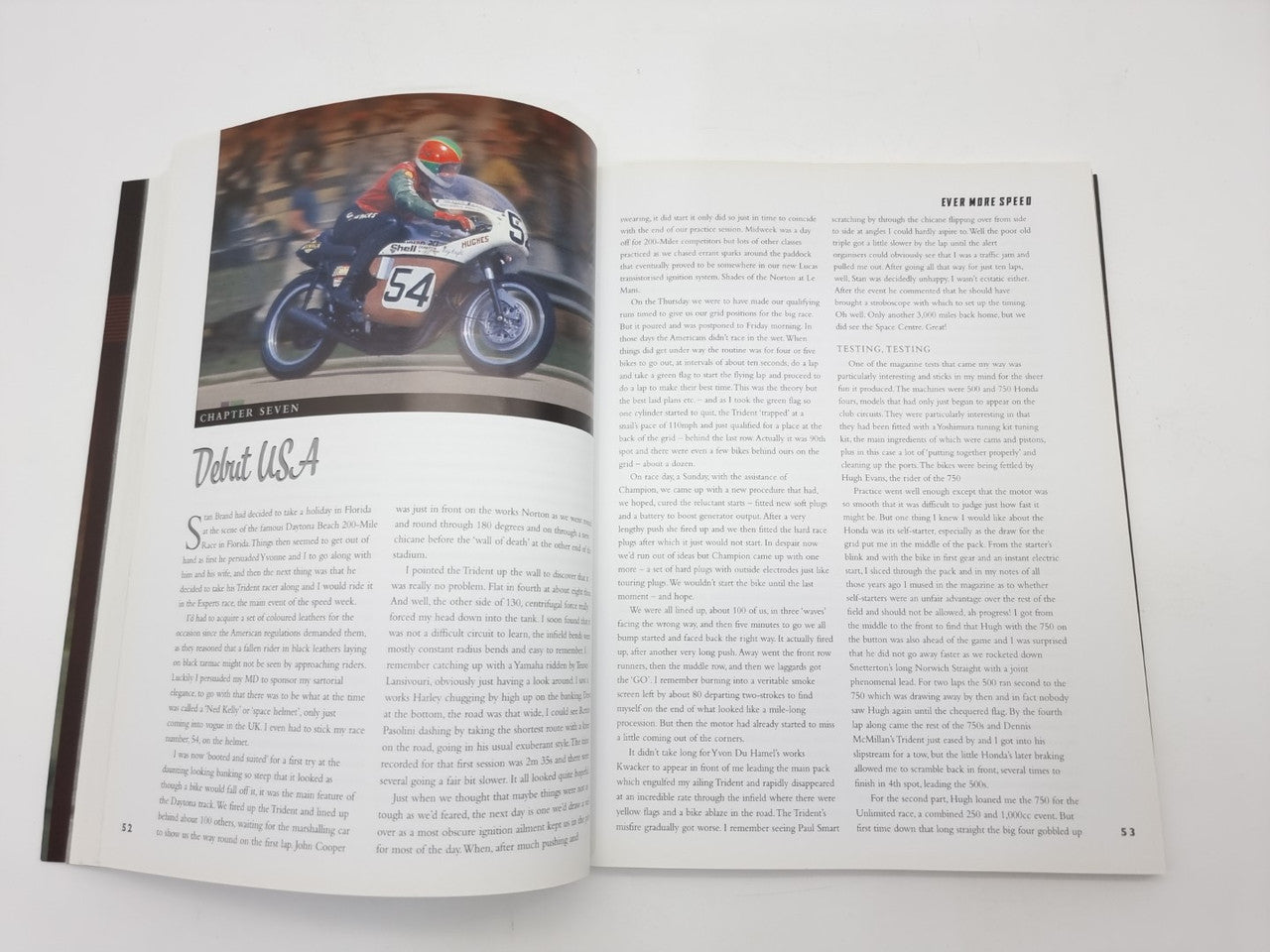 Open autobiography book with motorcycle race photos and two columns of text pages