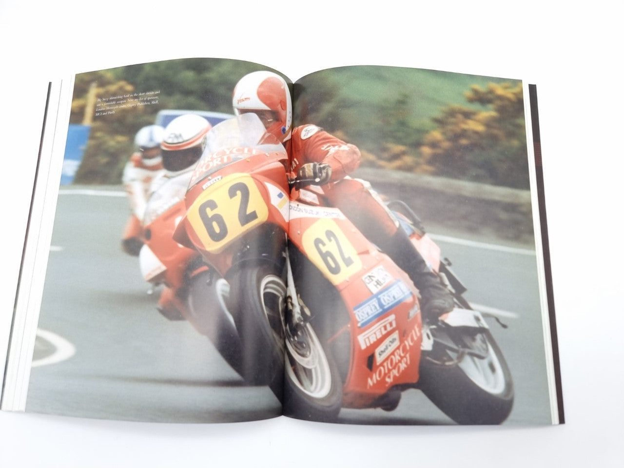 Open book with close-up orange race motorcycle on left page and text on right