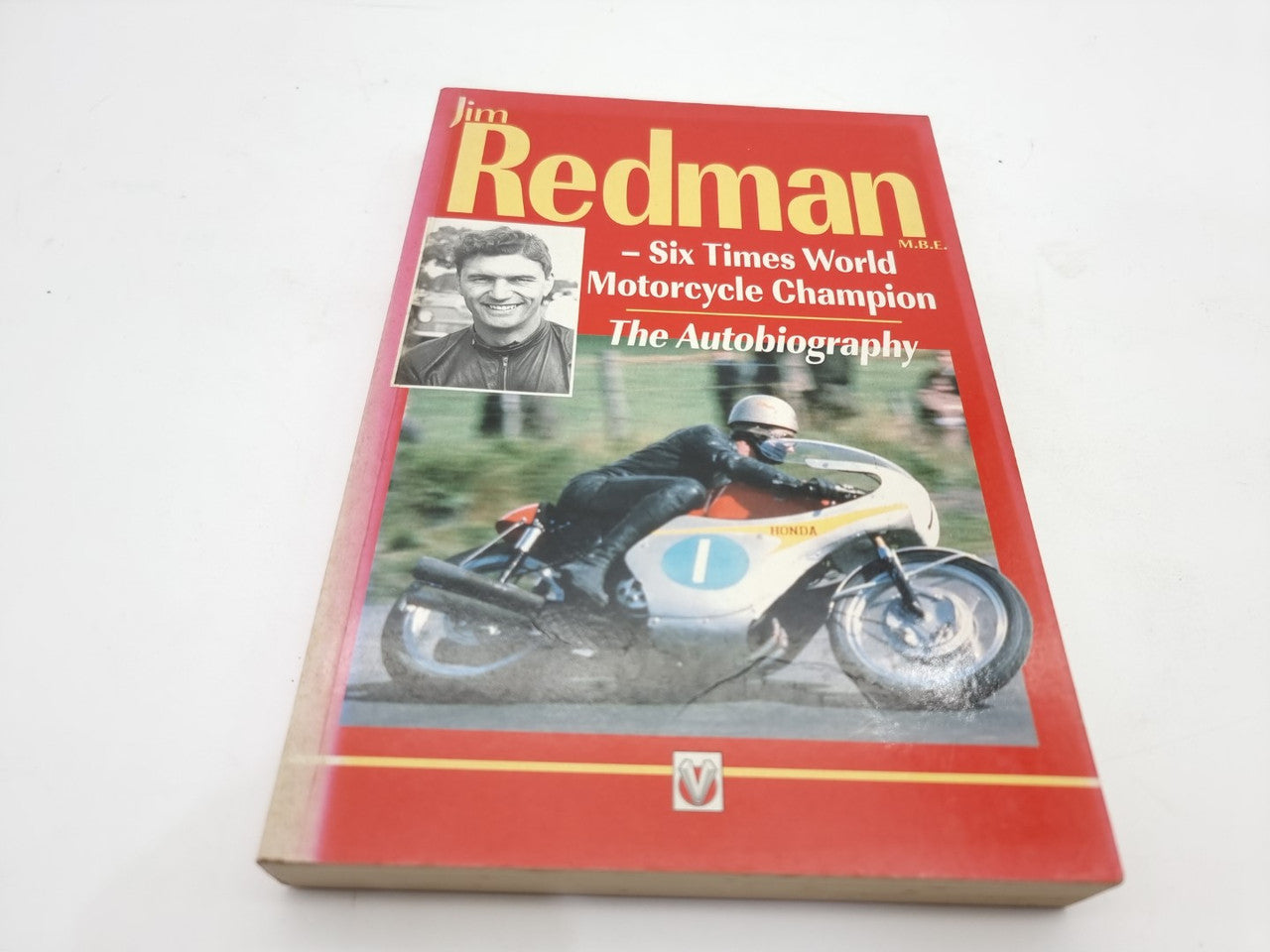 Red hardcover motorcycle autobiography book with Jim Redman name and racing bike on cover