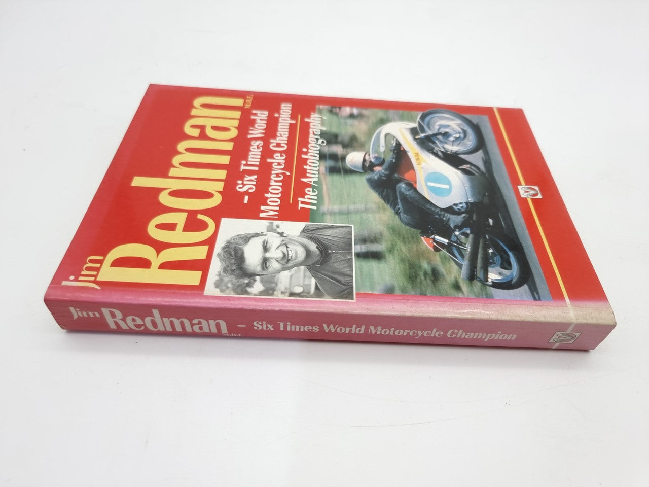 Red hardcover motorcycle autobiography book, angled view of cover with portrait and bike