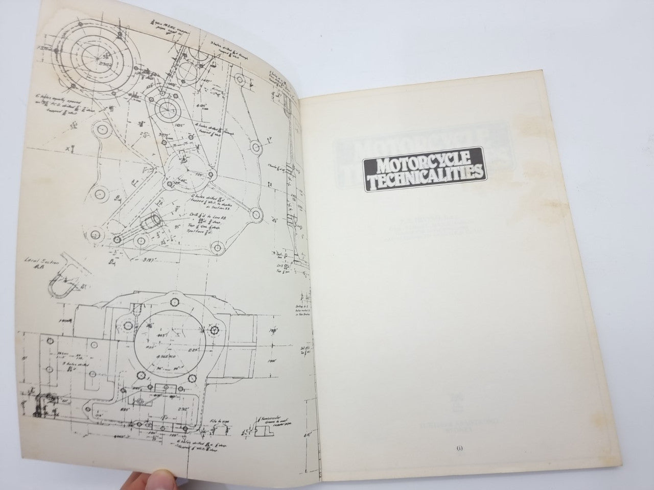 Motorcycle technicalities book open with detailed mechanical blueprint diagrams
