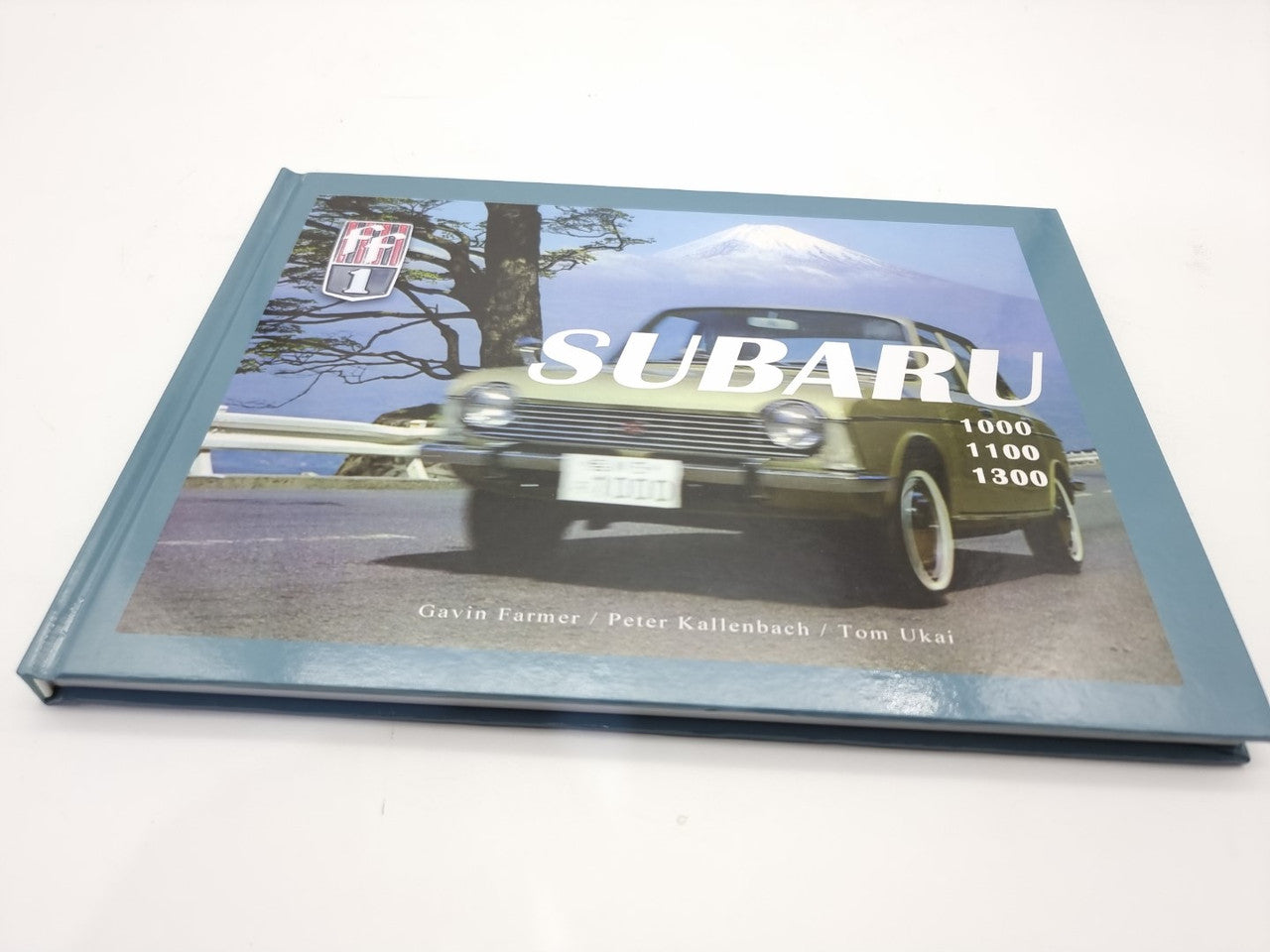 Subaru 100, 1100, 1300 book lying flat, front cover with classic yellow Subaru car and “SUBARU”