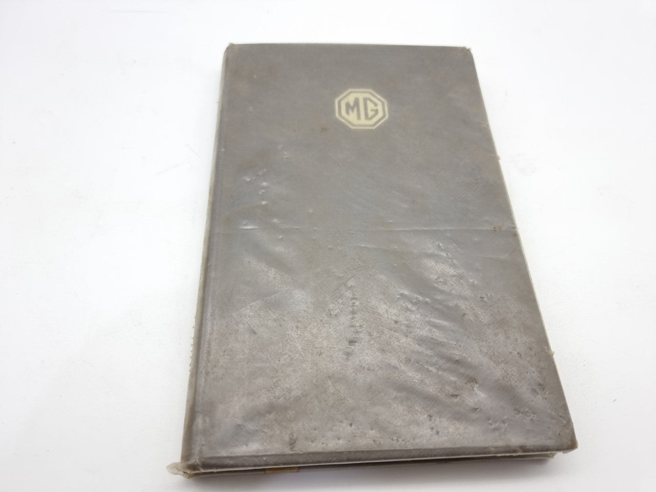 Closed vintage car maintenance manual with dark cover and MG logo