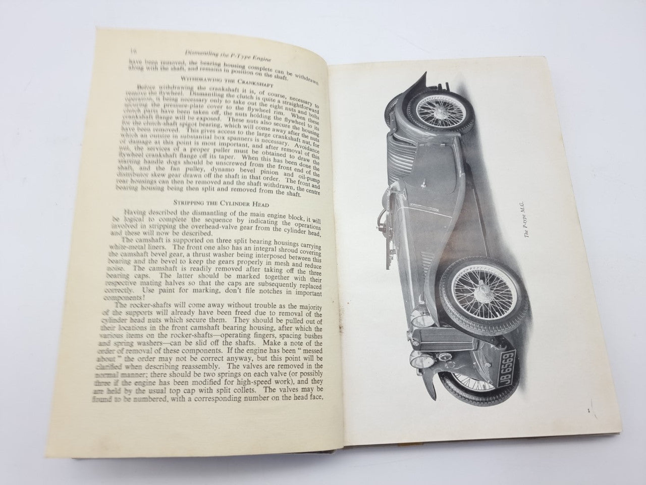 Open vintage car maintenance manual with engine photo illustration and text pages