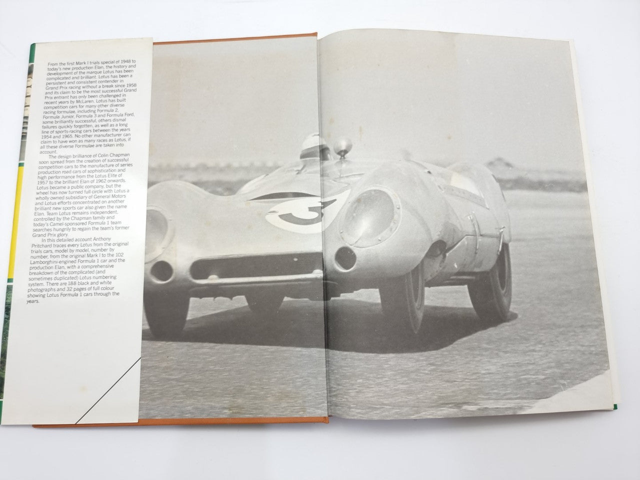 Open book showing black-and-white pages with a racing car photo and printed text