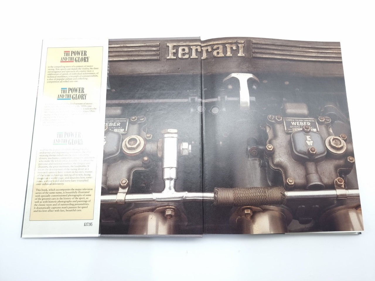 Motor racing history book open to Ferrari engine bay photo and article pages