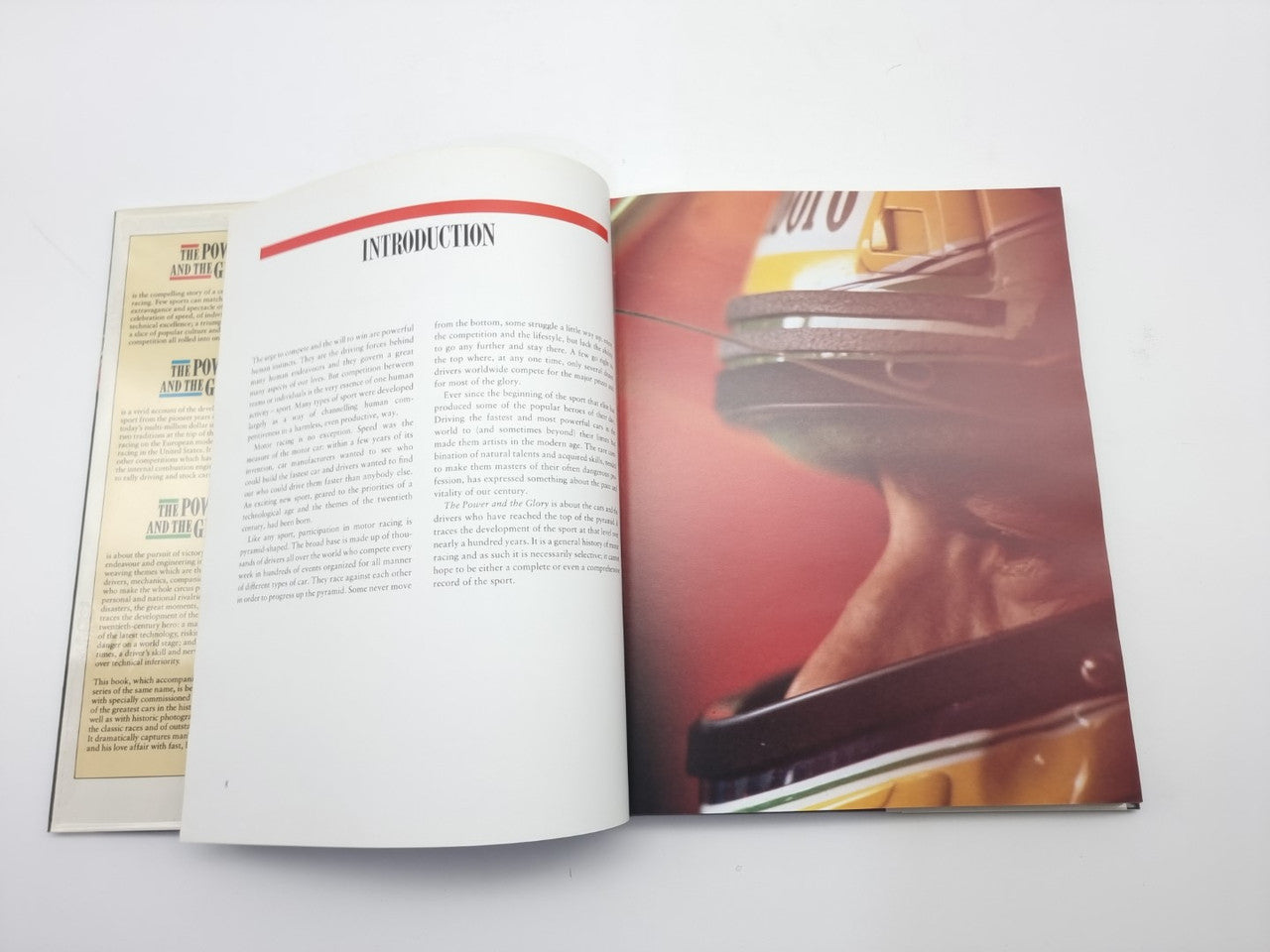 Motor racing book open to introduction pages with text and colorful driver cockpit photo