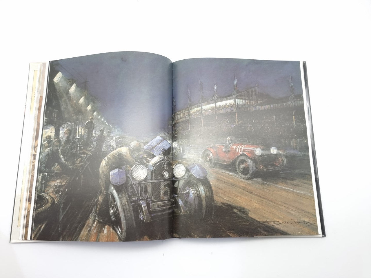 Motor racing book open spread with grayscale race car image on a track at night