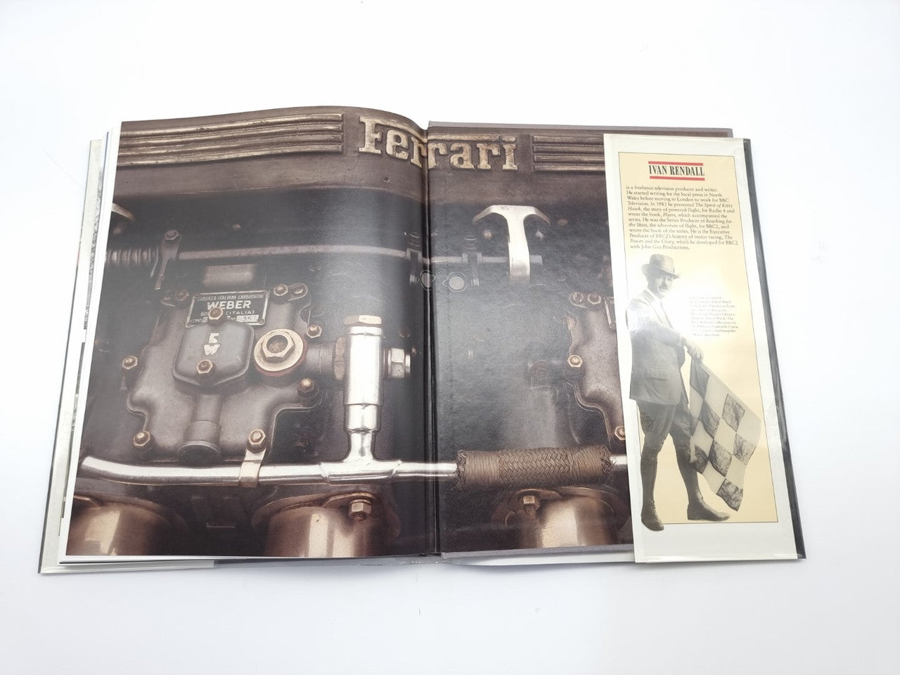 Motor racing book open spread with Ferrari engine-detail photo and a guide graphic