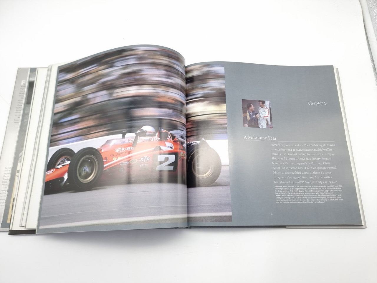 Open motorsport book spread with action race car photo and a chapter text panel.