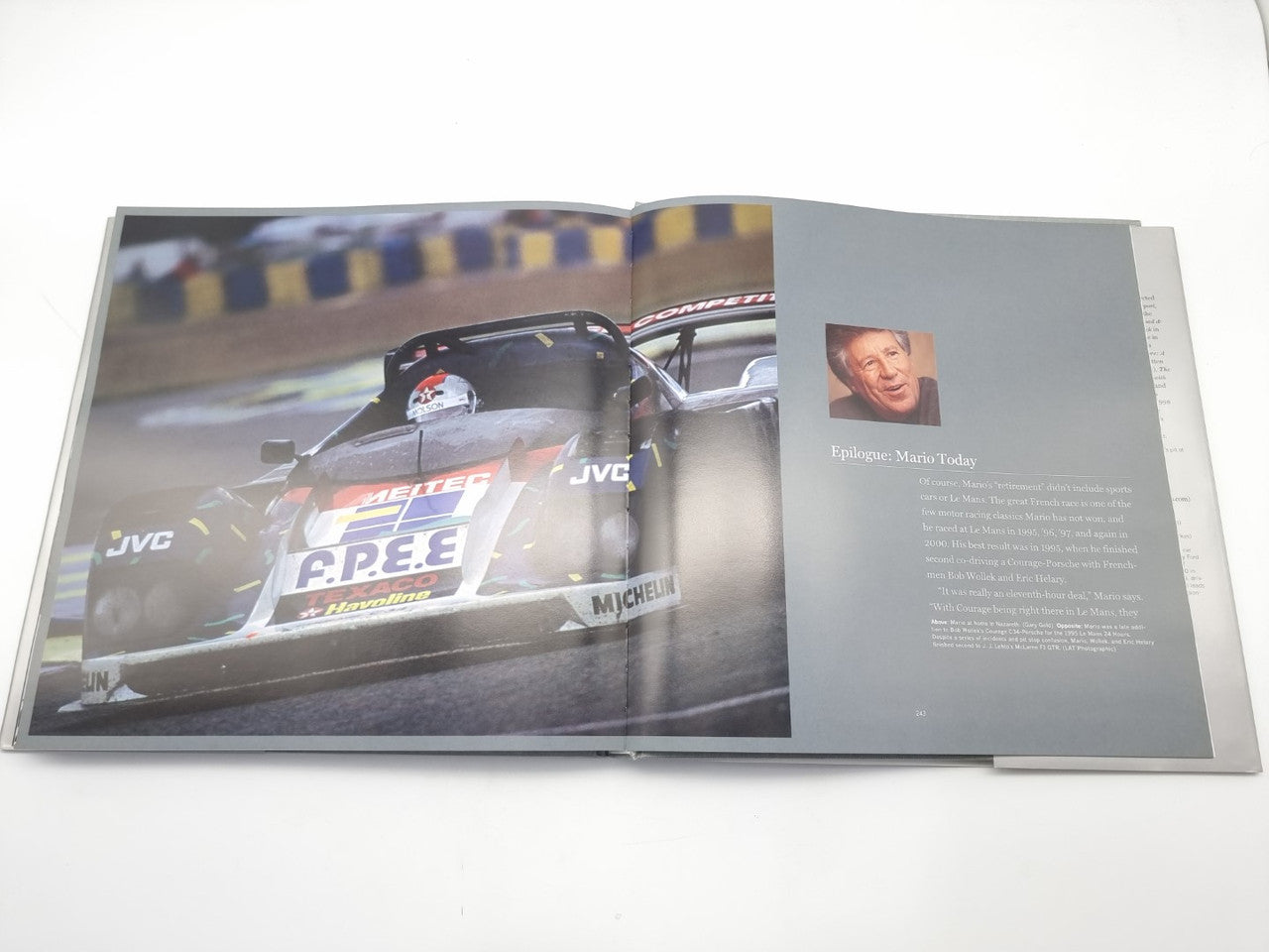 Open motorsport book with close-up race car photo and author portrait text panel.