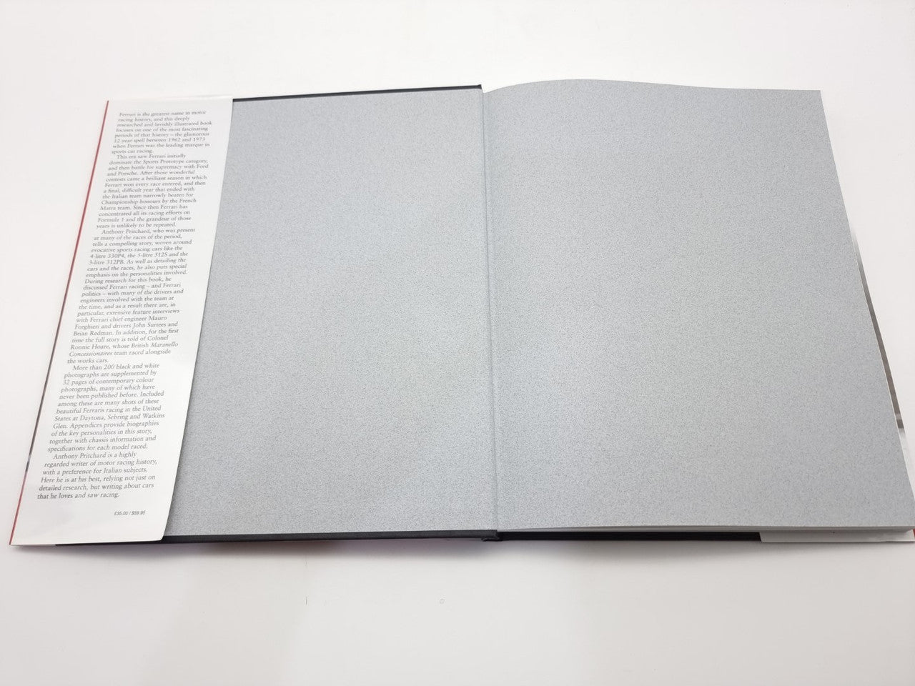 Opened automotive history book with blank gray pages and visible page edges