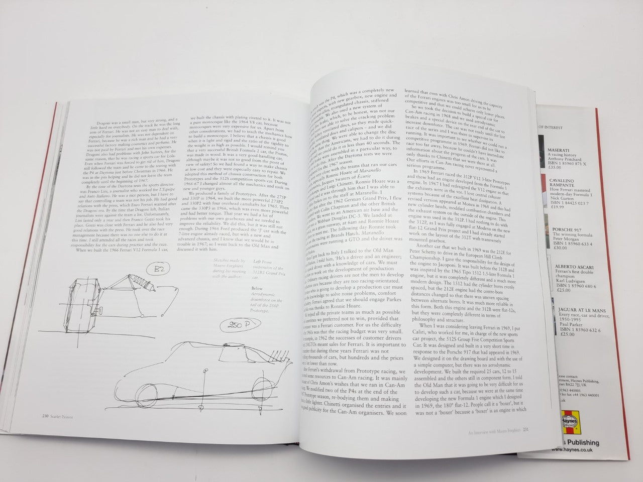 Open automotive history book with engineering sketches and dense text pages