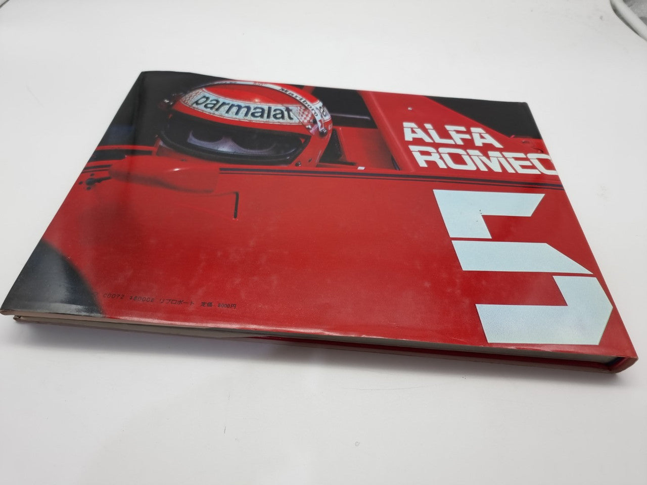 Hardcover book with red Alfa Romeo racing cover artwork and car graphic