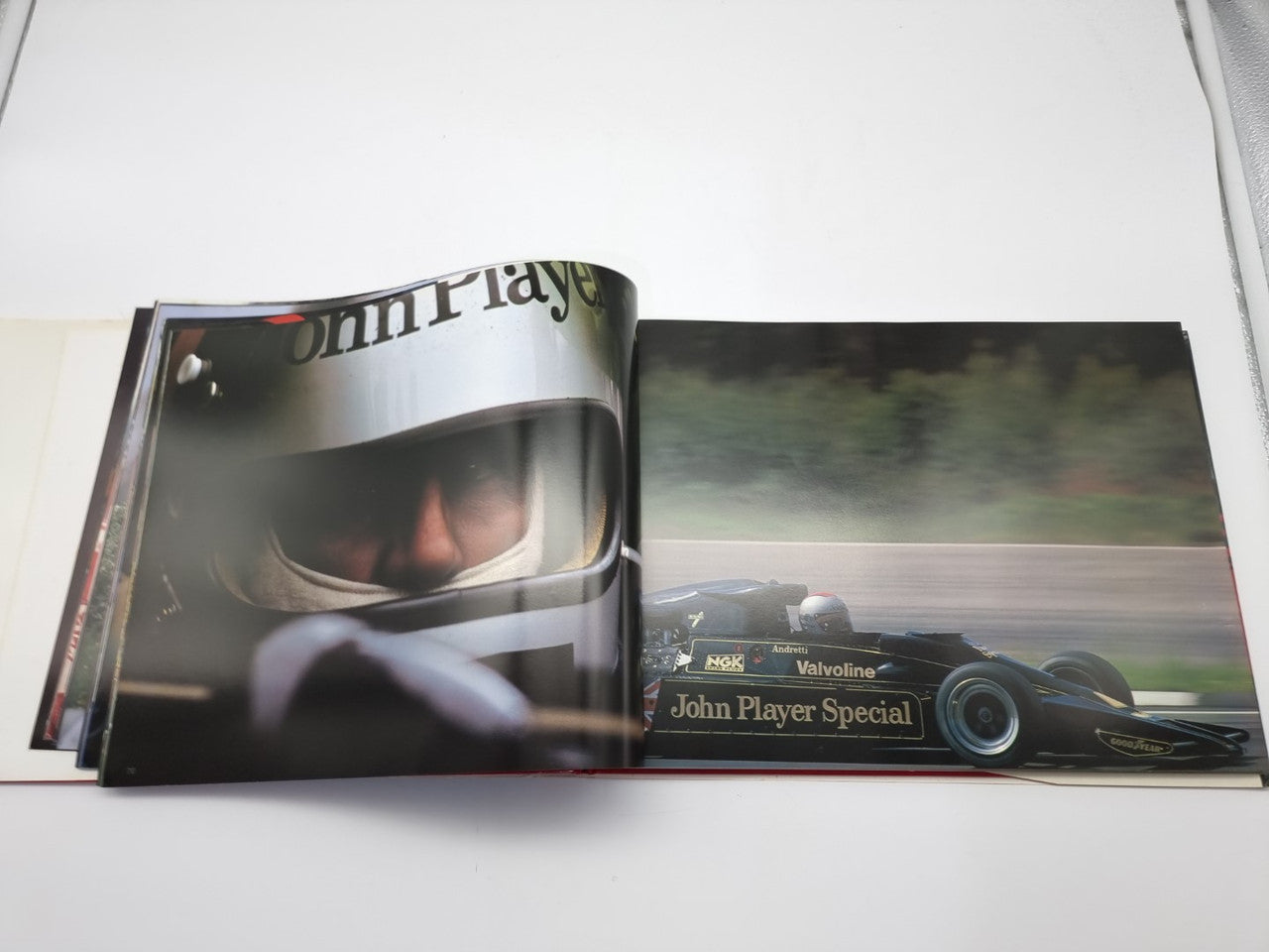 Open motorsport photo book with close-up helmeted driver on left and race car action