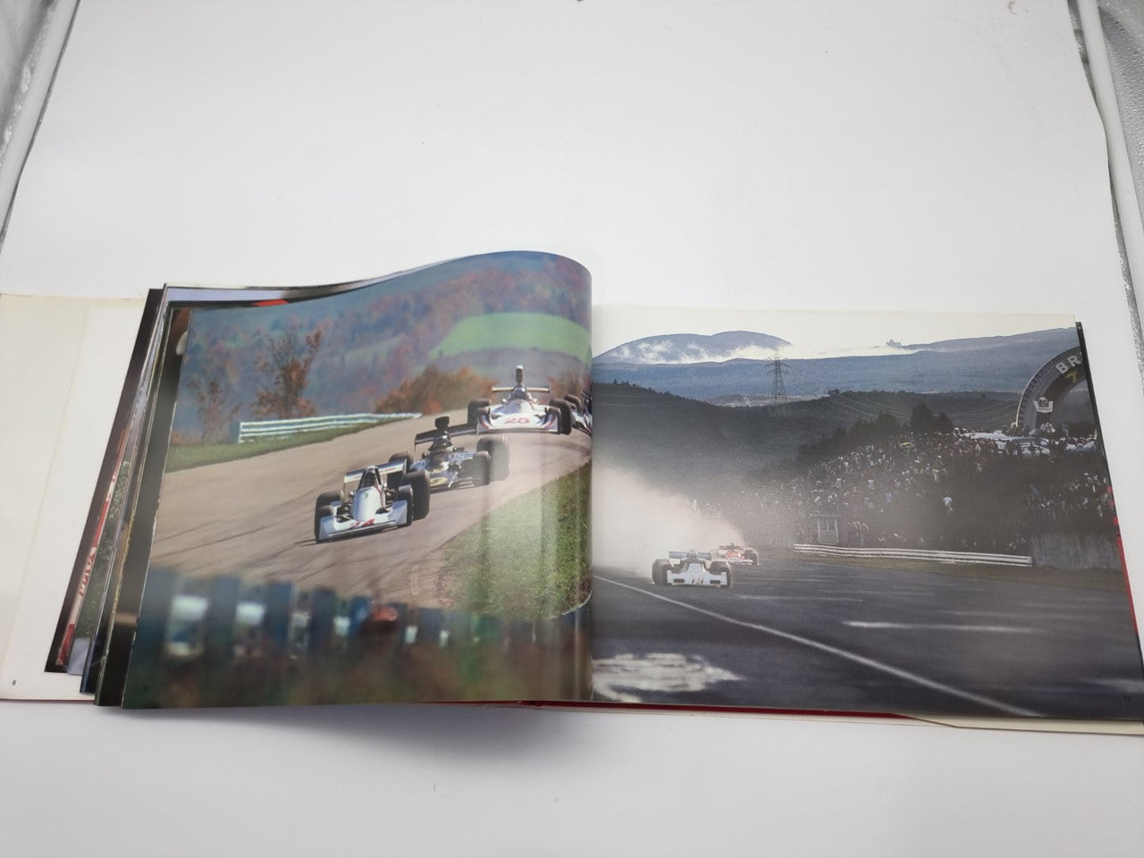 Open motorsport photo book with multiple race cars on track across two pages