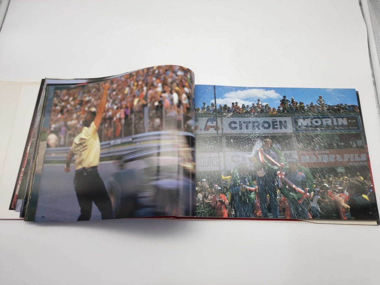Open motorsport photo book with crowd and trophy celebration on two facing pages