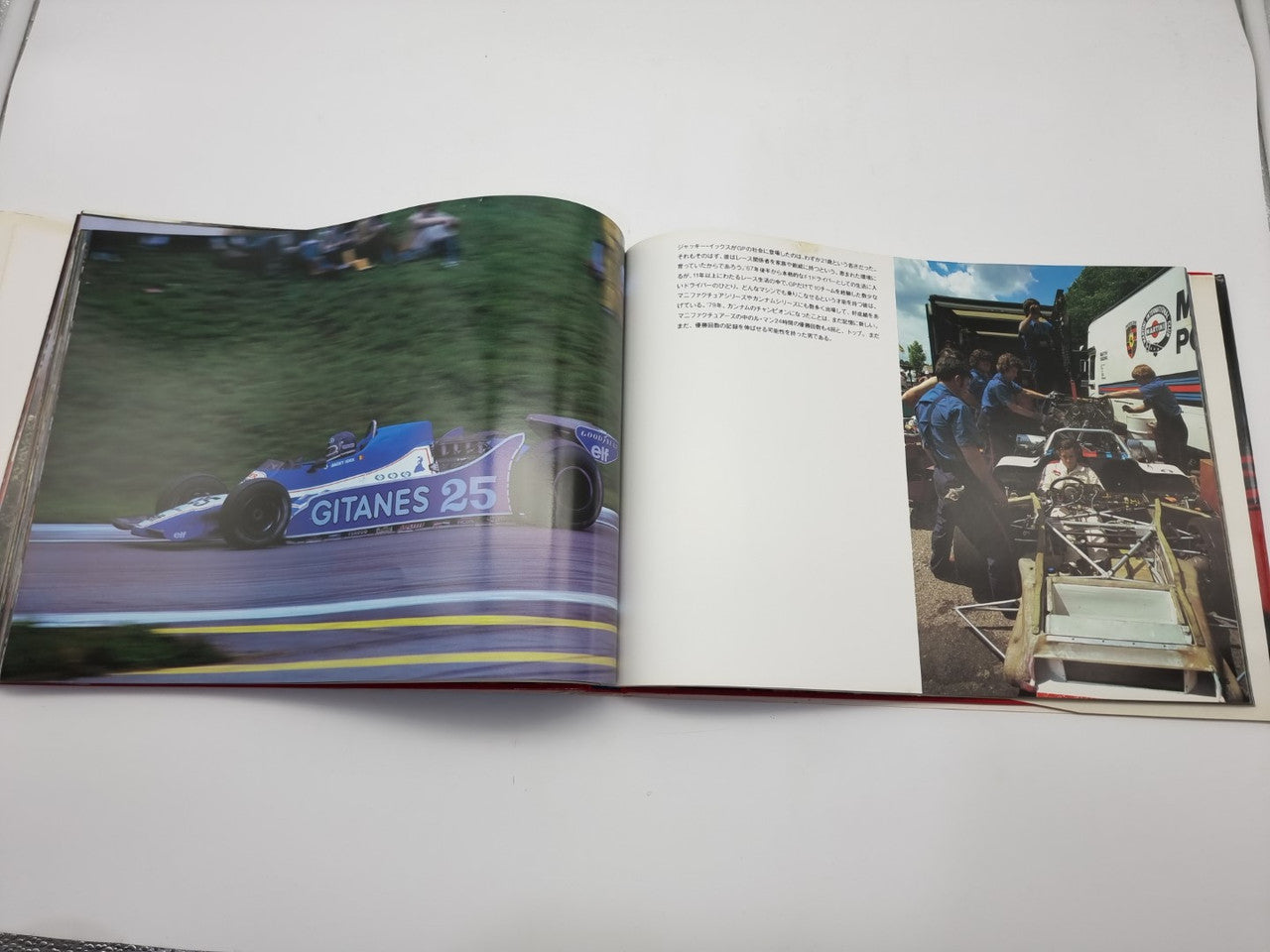 Open motorsport photo book with blue race car on left and pit crew scene on right