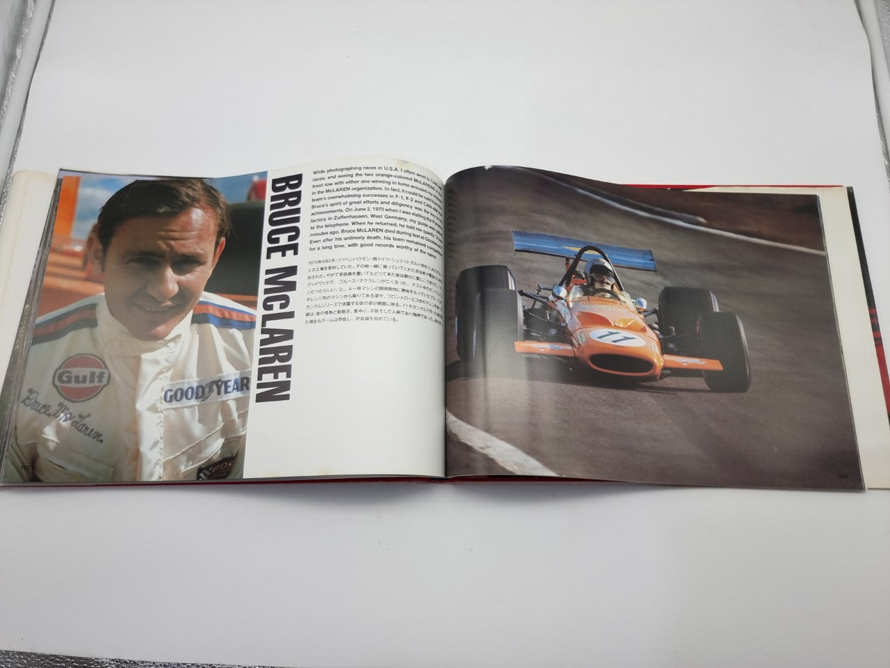 Open motorsport photo book with racing driver on left and orange race car on right
