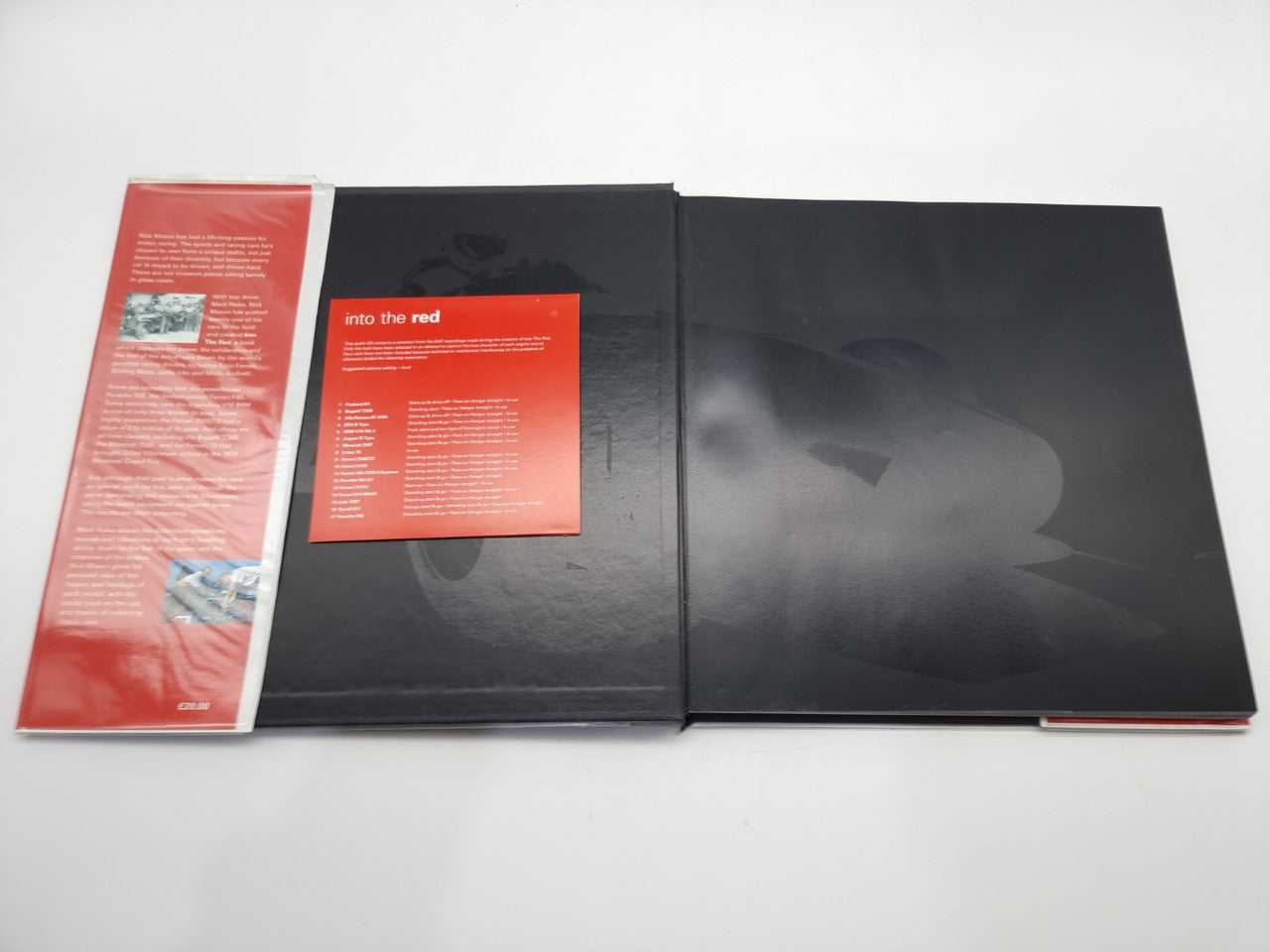 Hardcover motorsport history book opened, showing red insert pages and dark cover