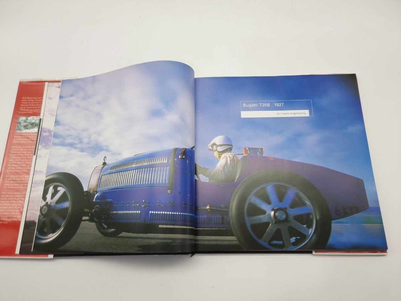 Open motorsport history book spread with blue sky and race car image