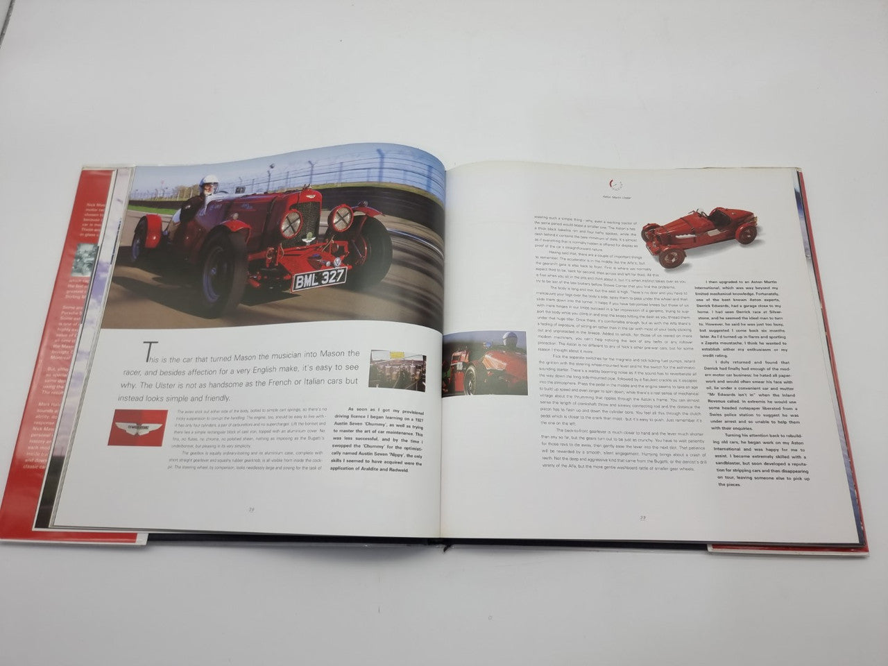 Open motorsport history book spread with red car photos and dense text columns