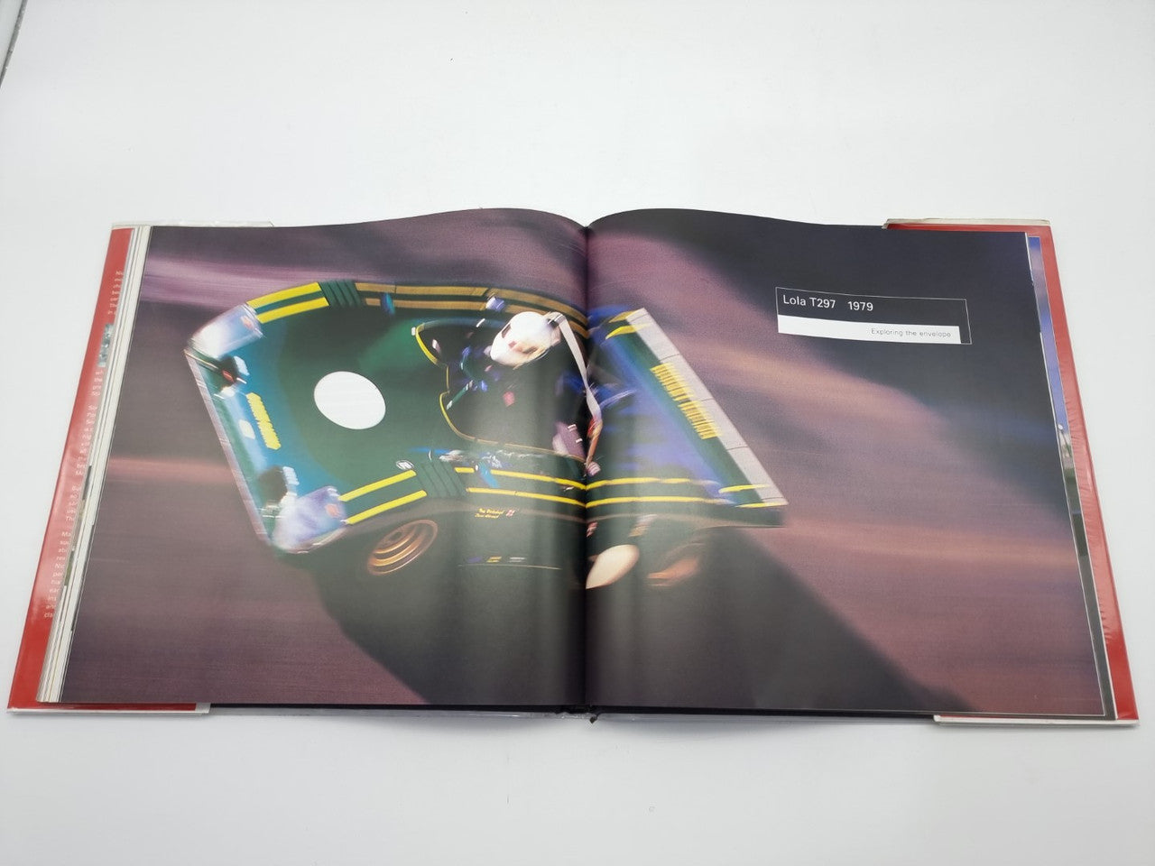 Open hardcover book showing a cockpit view of a race car on a two-page spread