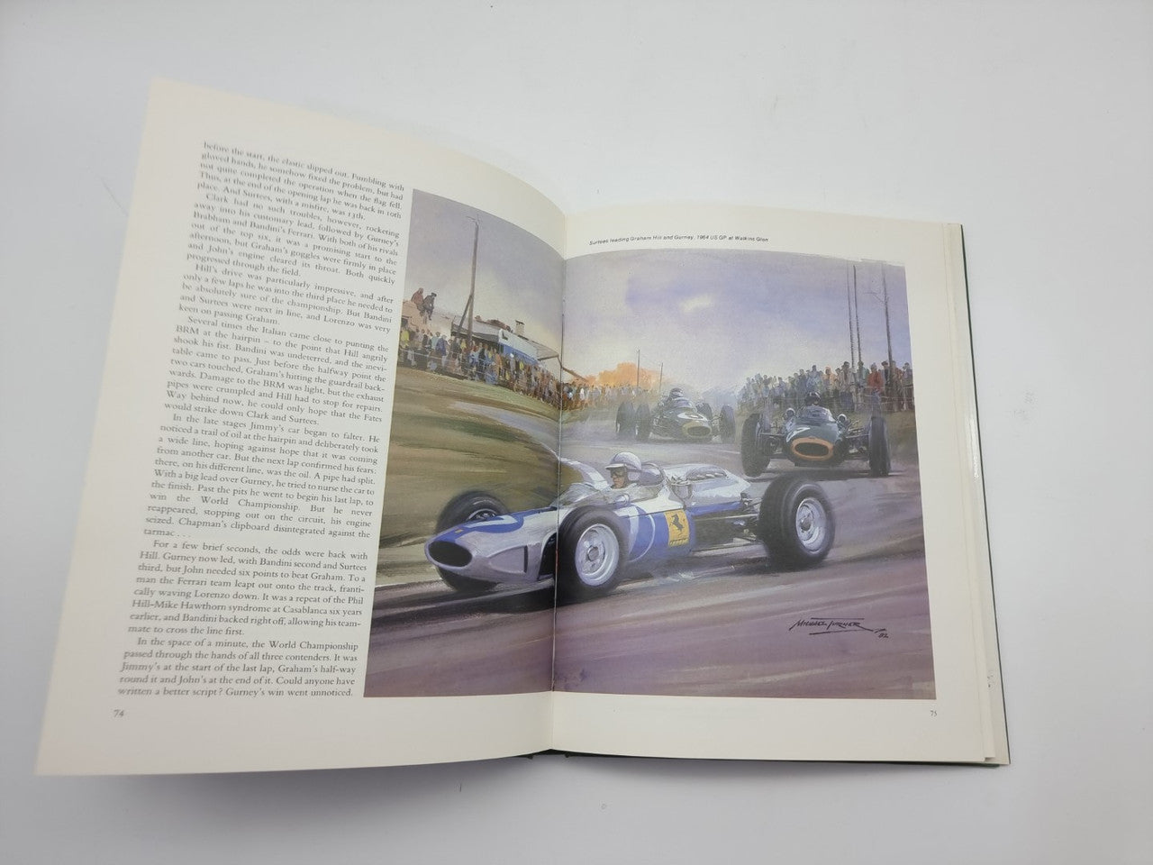 Open Formula One art book with race car painting on right and text on left