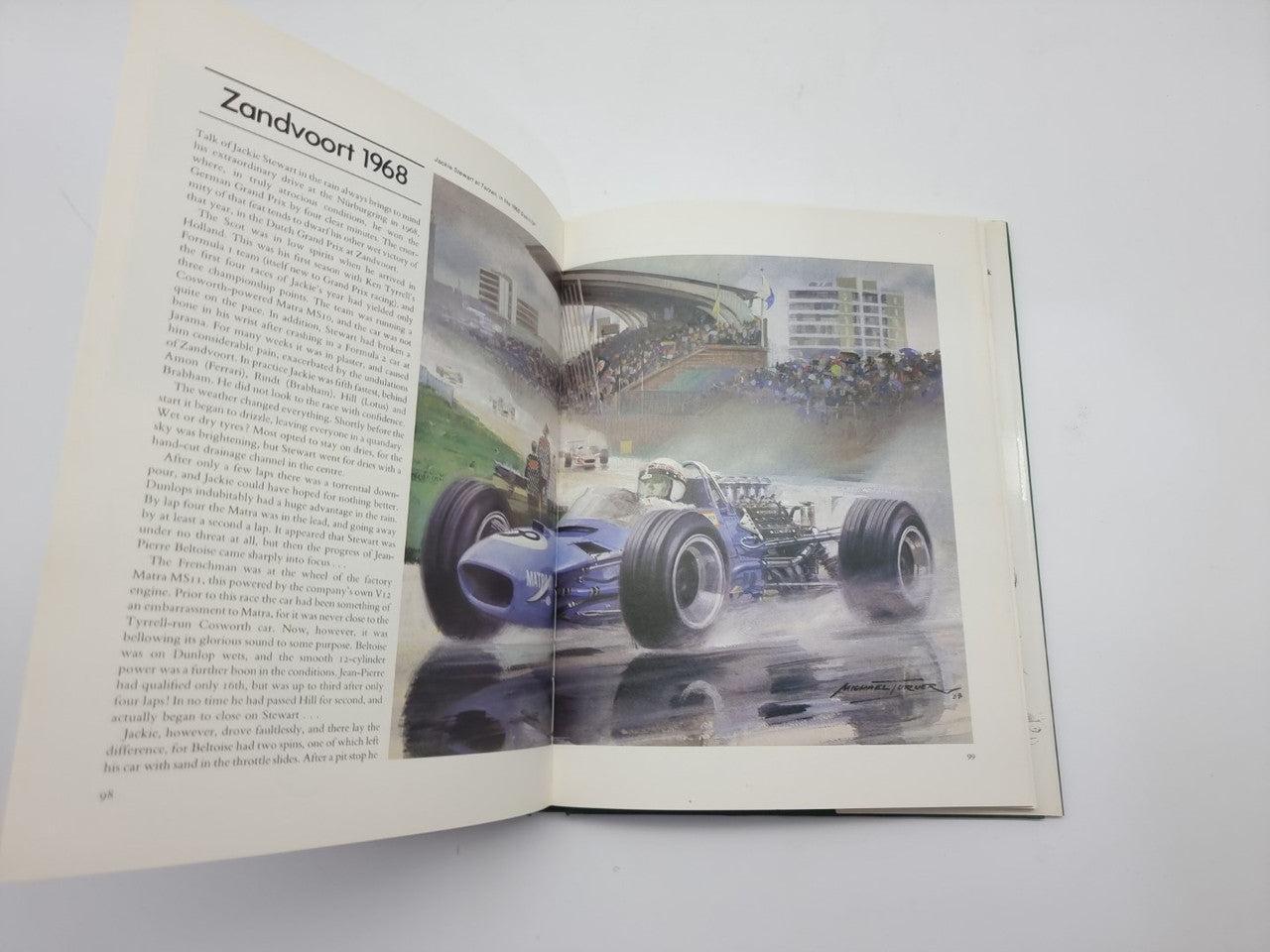 Open Formula One art book with Zandvoort 1968 racing car painting on right