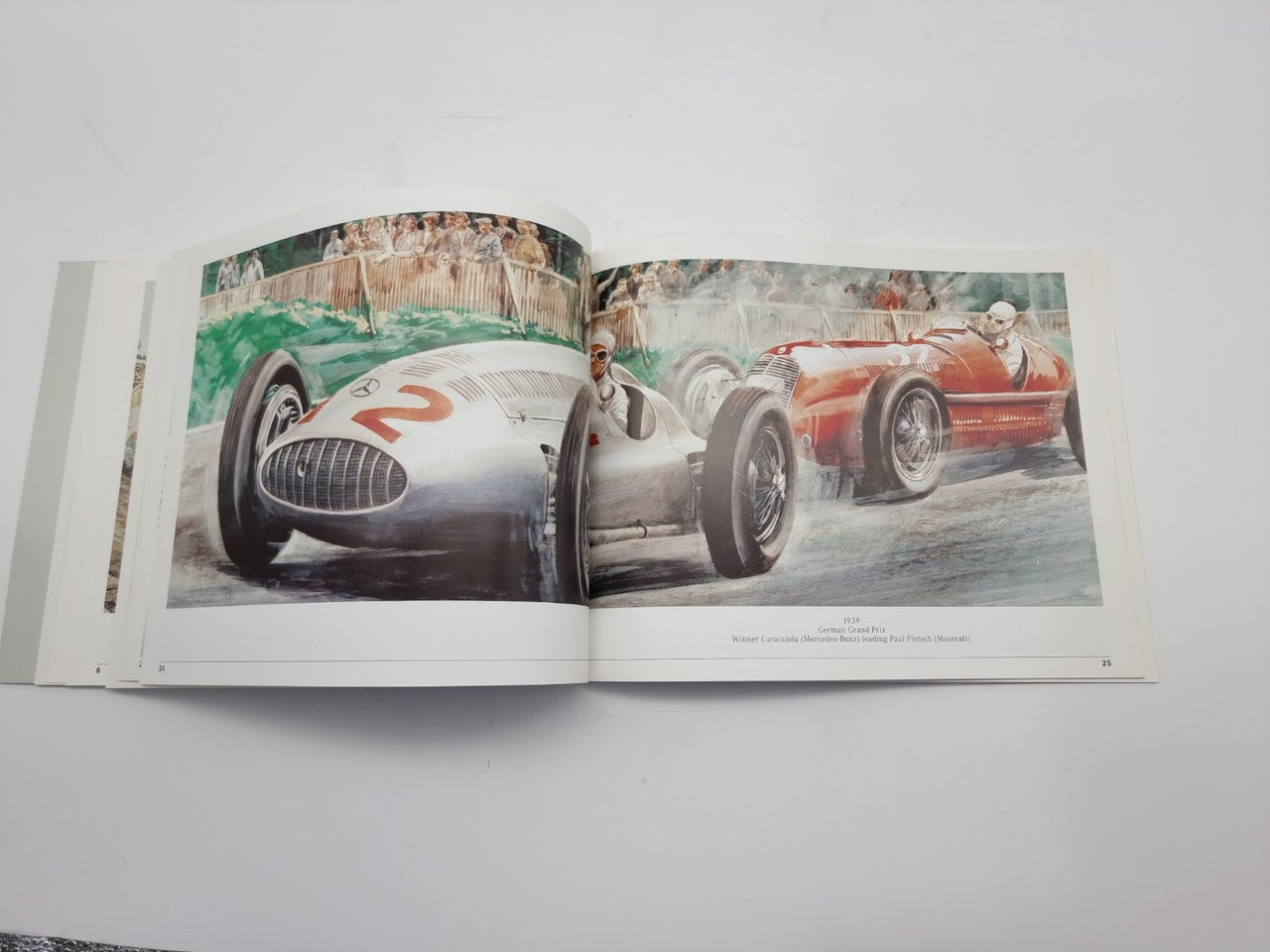 Motorsport history book open spread with two vintage race cars on track, front views.