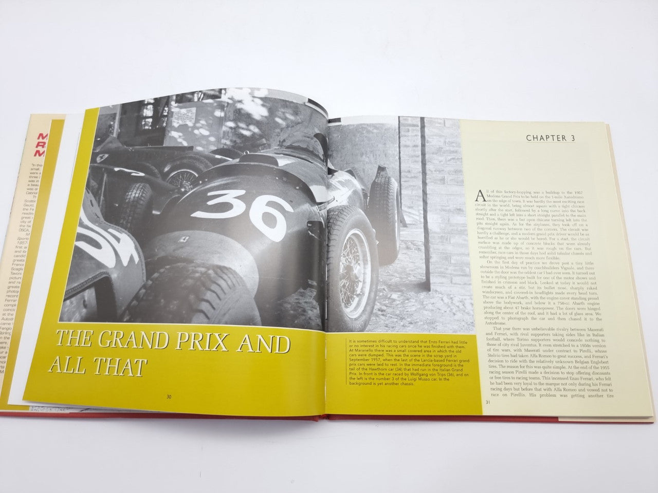 Open motorsport history book with black-and-white car photos and chapter headings