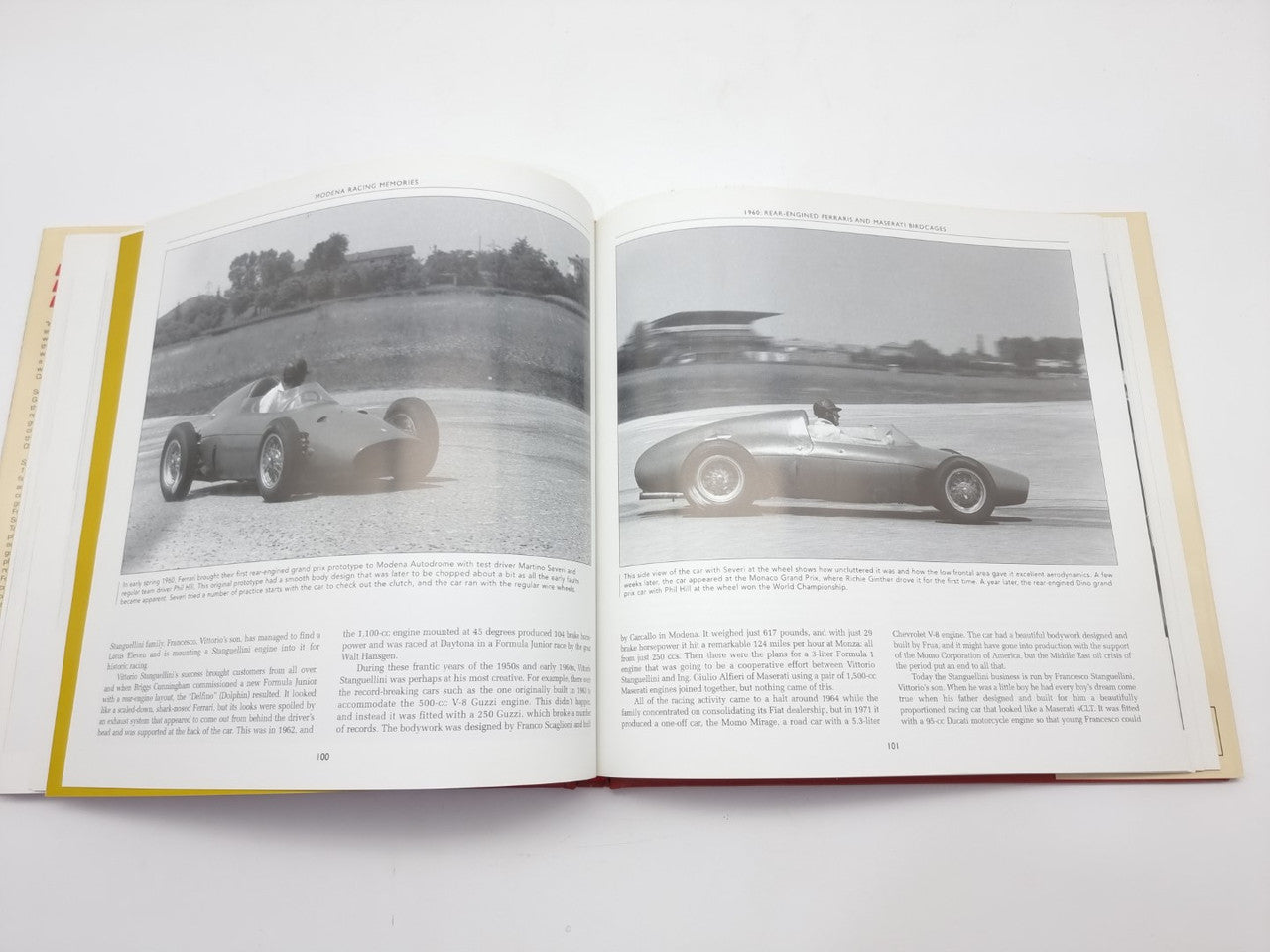 Open racing book with wide black-and-white photos of white race cars