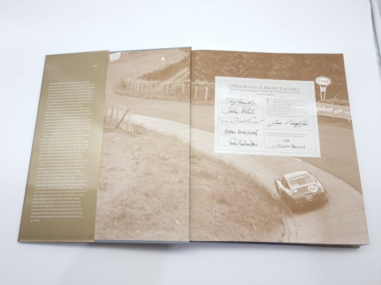 Opened hardcover book showing interior pages with vintage car photos and document page