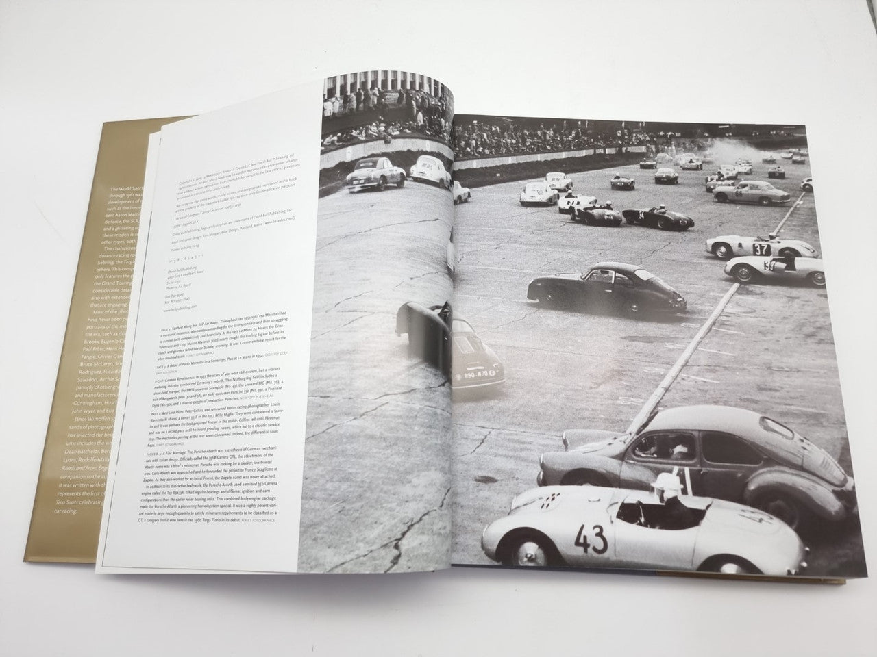 Opened hardcover book with black-and-white spread of vintage race cars on track