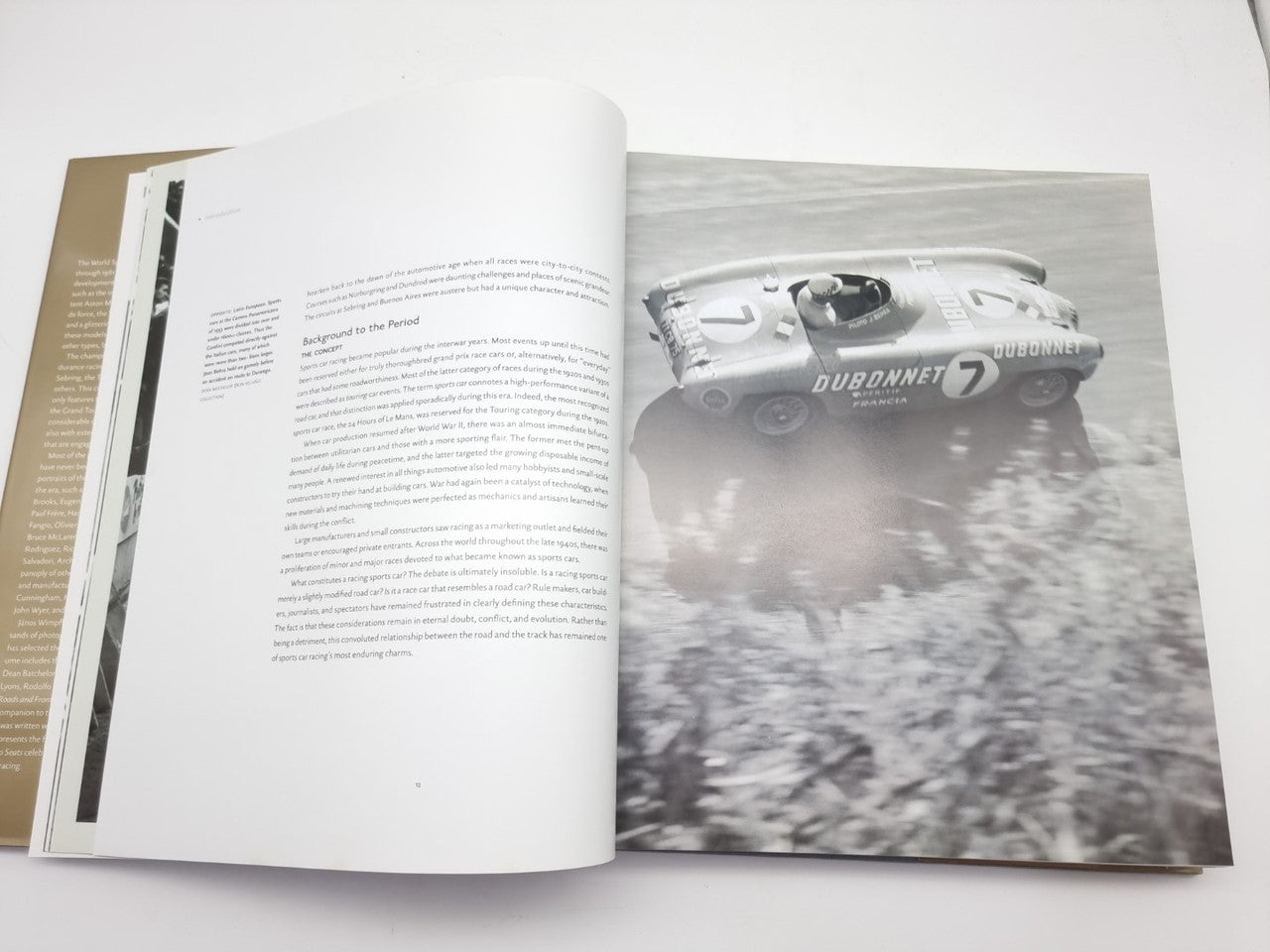 Open book with racing car photo spread and printed text pages.