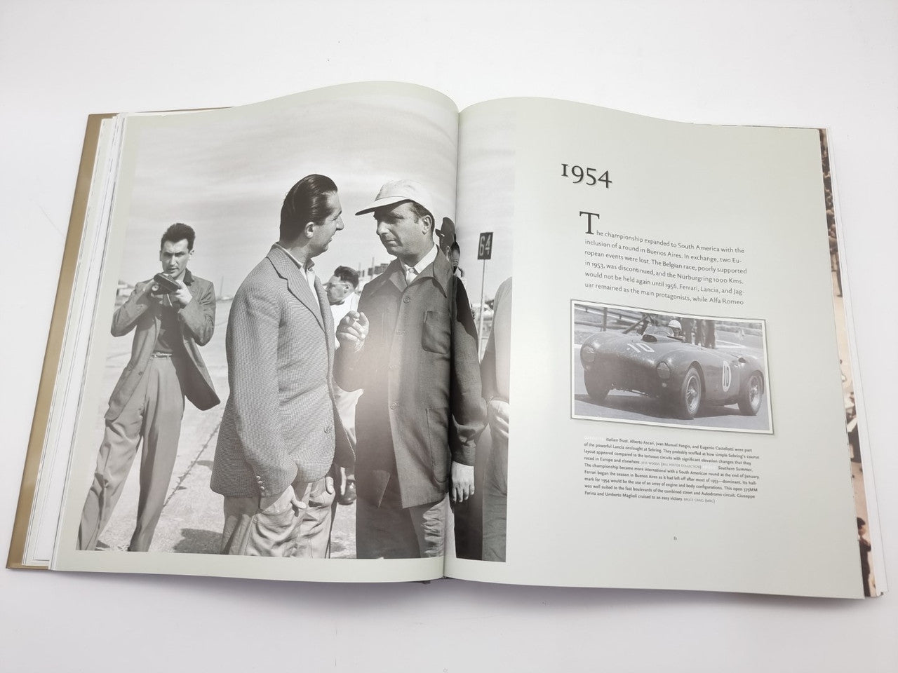 Open book with photo of men at track and page heading '1954'.