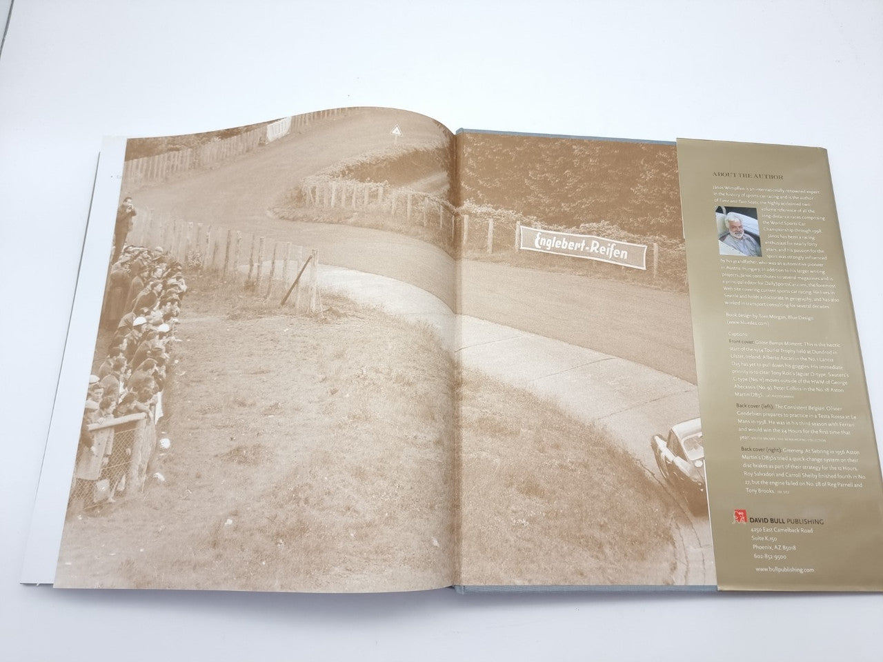 Open hardcover book with sepia photo of vintage cars and a biography panel