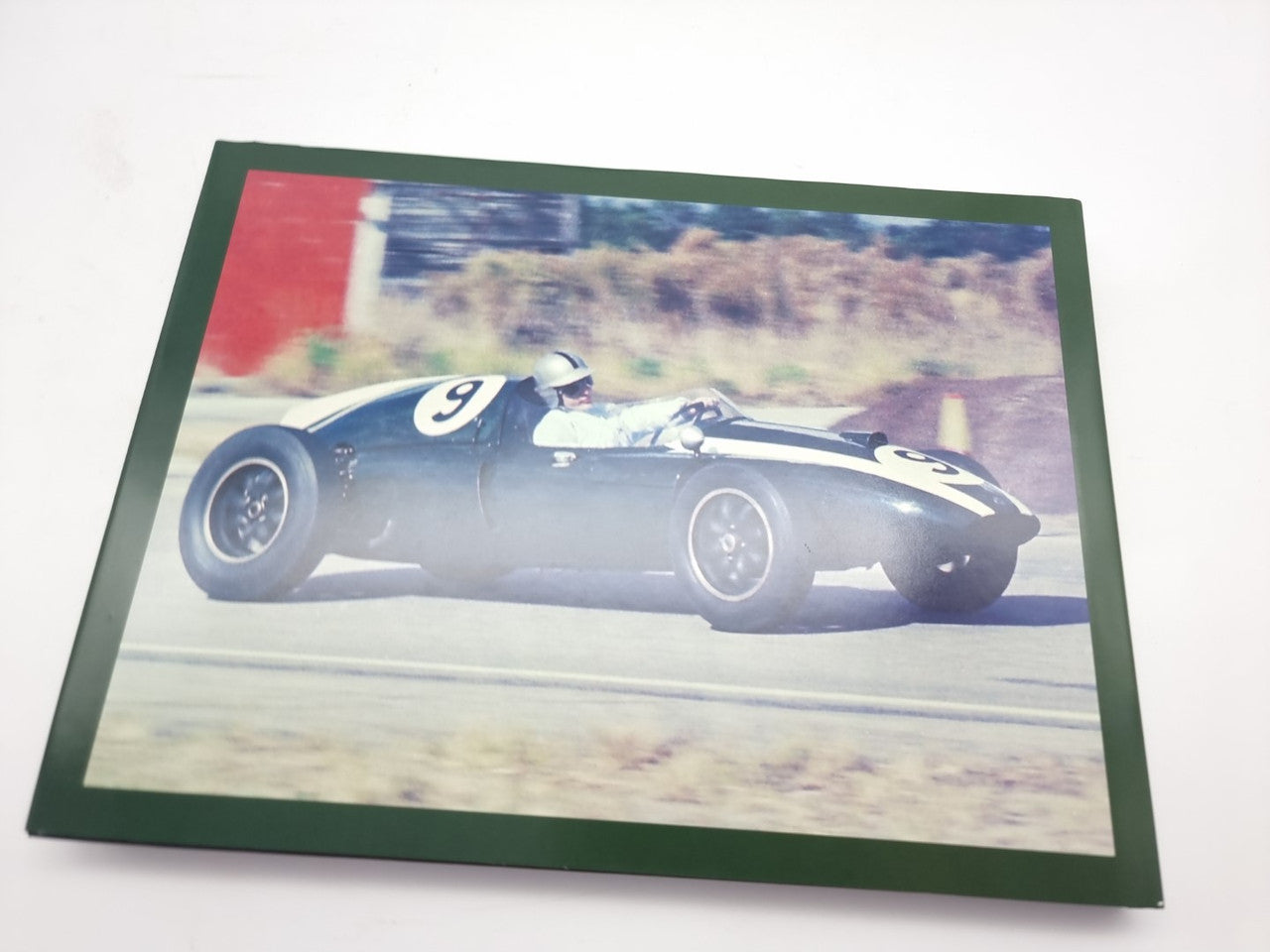 Hardcover racing book with green border and classic race car photo cover