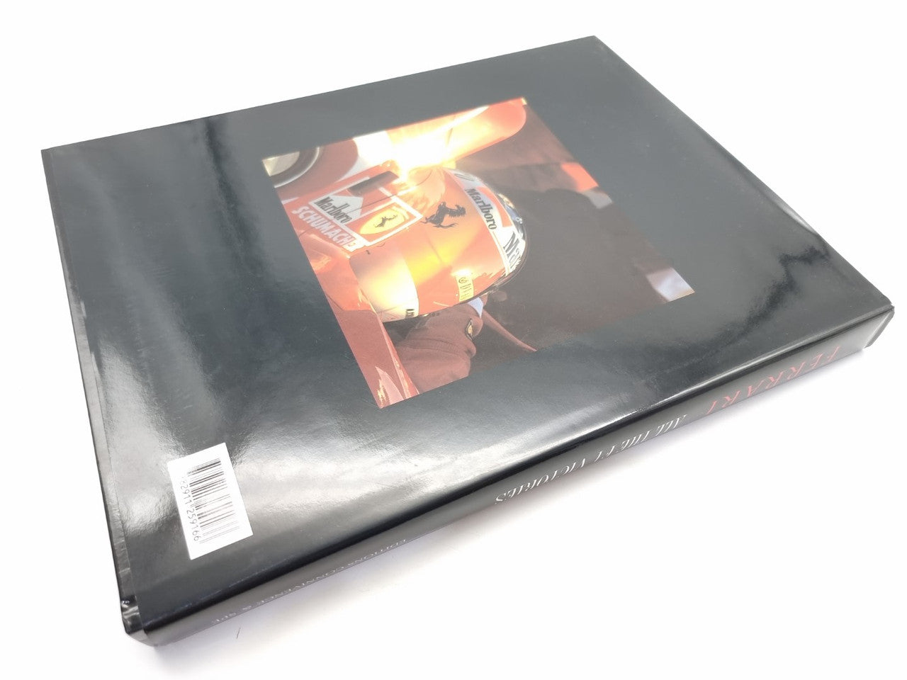 Ferrari F1 victories hardcover, closed top view with racing driver photo on dark cover