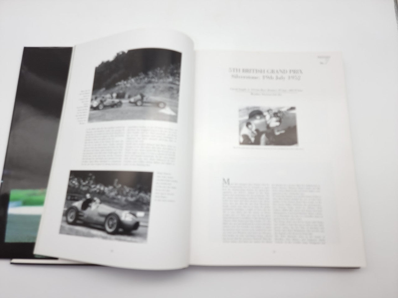 Open motorsport book with race photo spreads and dense paragraphs of text