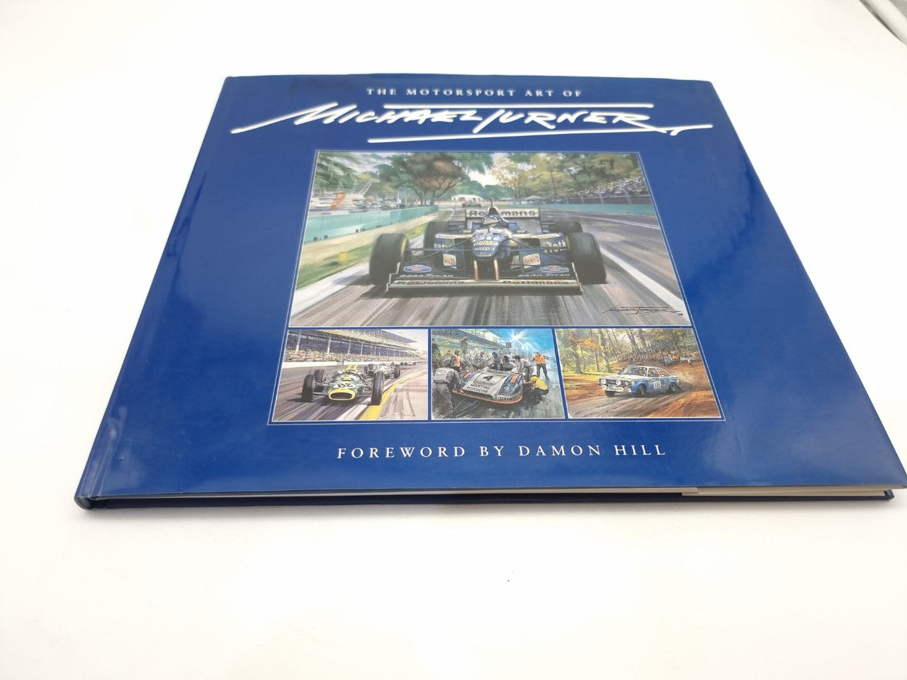 Blue hardback motorsport art book with cover collage and title text