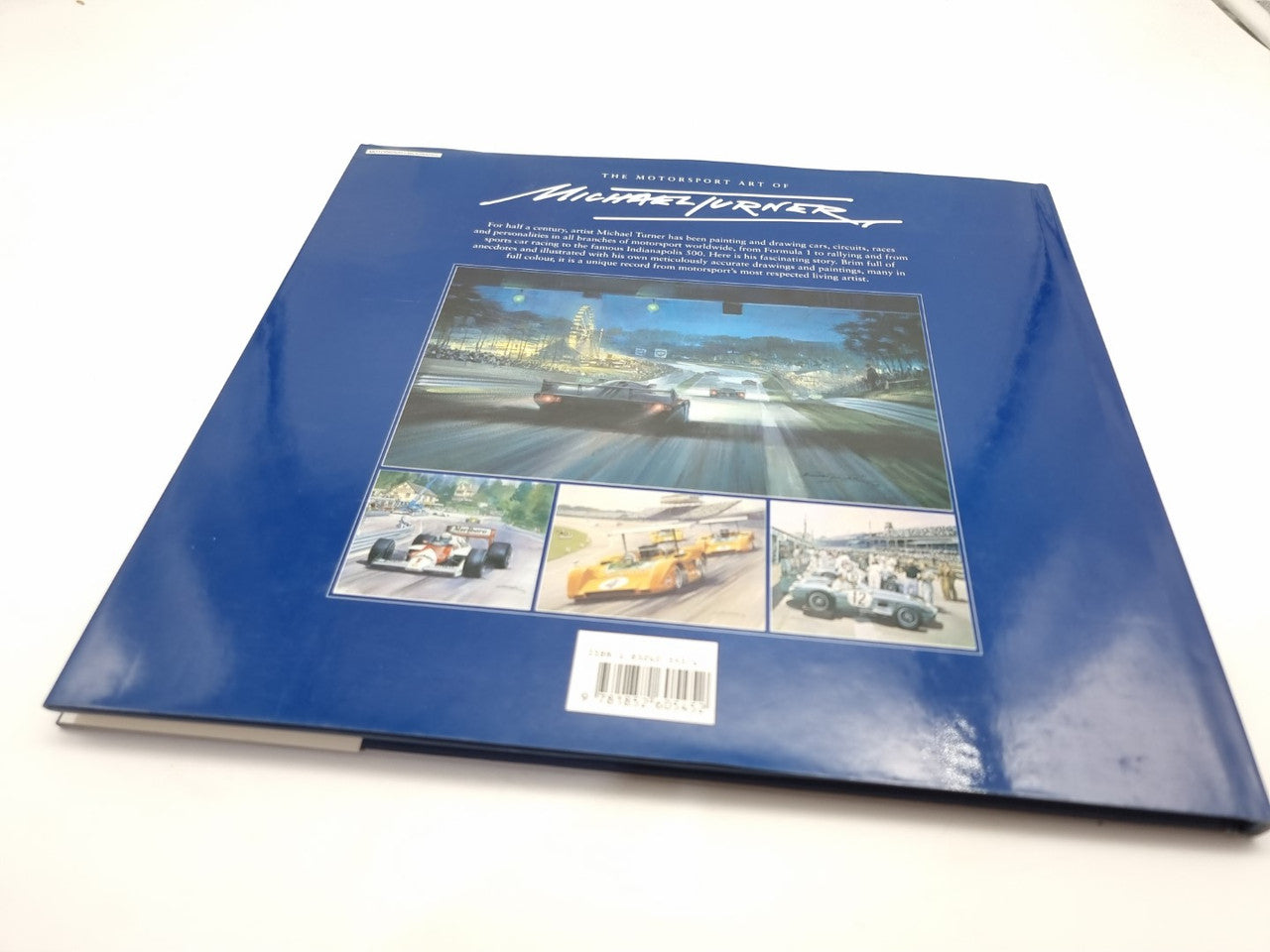 Blue hardback motorsport art book back cover with barcode and photo collage