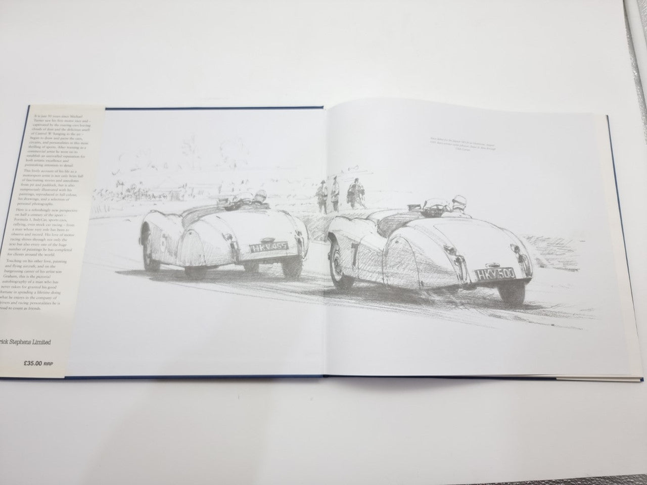 Open motorsport art book showing black-and-white sketch of race cars on page spread