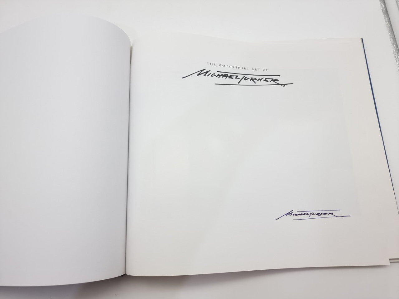 Open motorsport art book inside covers with author signature and title mark