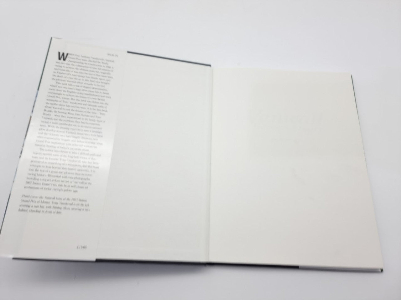 Open motorsport book spread with text on the left page and blank right page