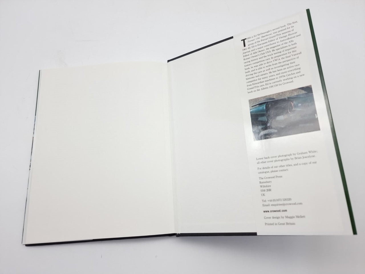 Open motorsport book spread with mostly blank pages and a small photo on right