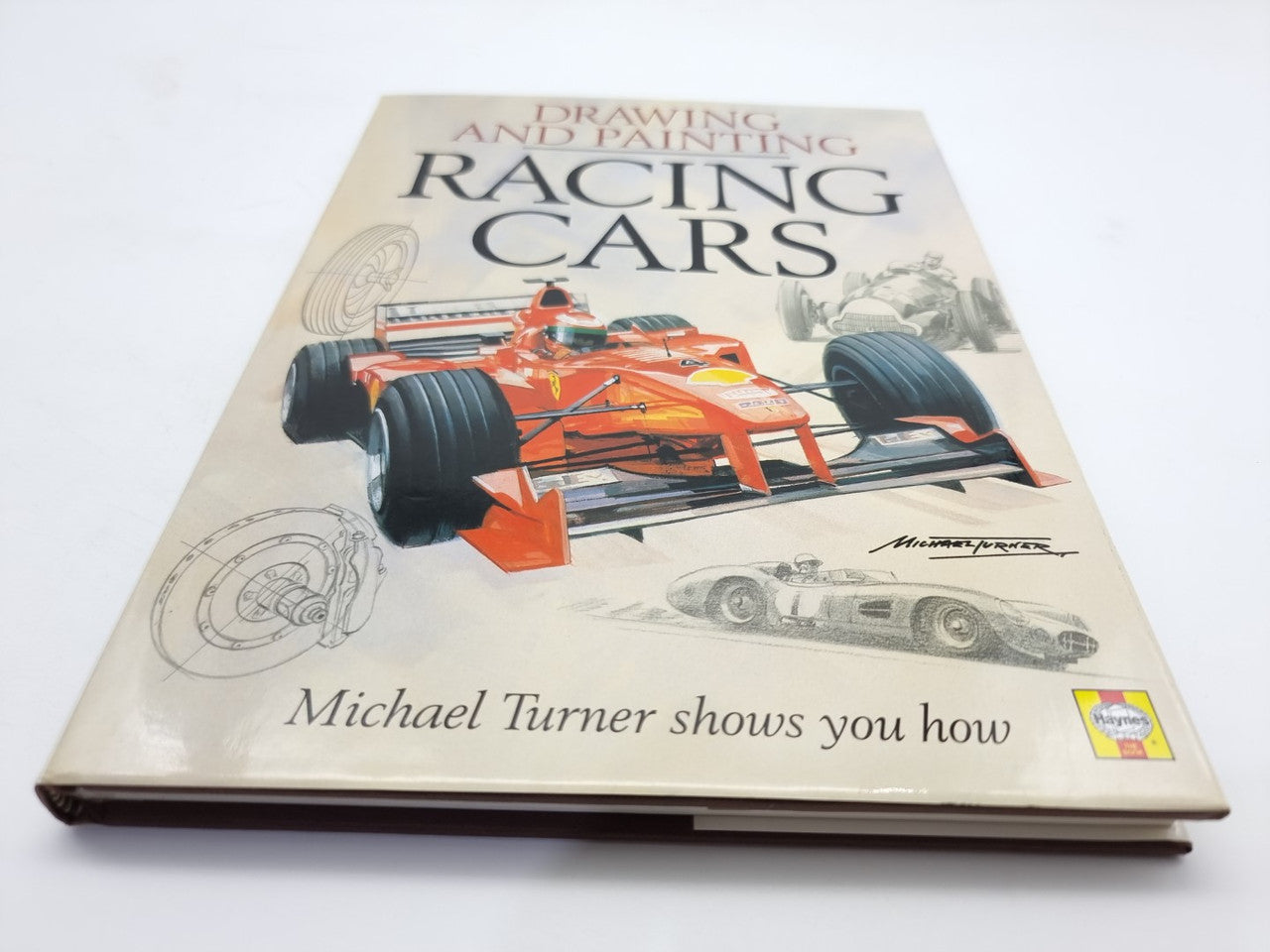 Racing cars drawing and painting book with orange race car cover, angled on desk