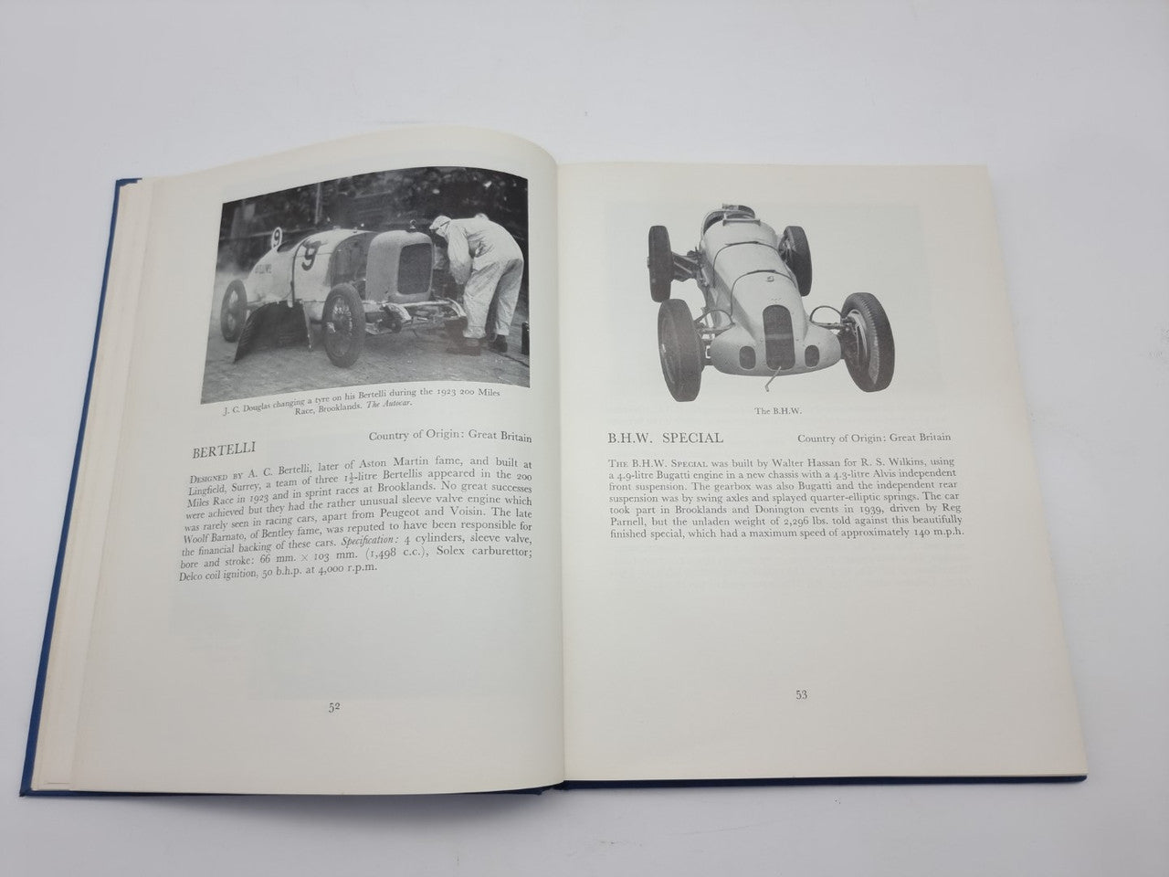 Open racing cars history book with vintage car photos and printed captions on both pages